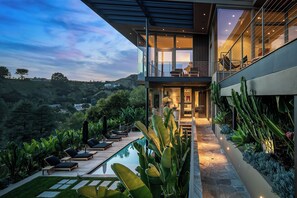Uma casa moderna com piscina, área de estar ao ar livre e vista para as colinas.