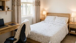 Une chambre à coucher comprenant un lit, un bureau, une chaise et deux lampes de chevet.