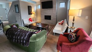 Una sala de estar moderna con un sofá verde, un sillón rojo, una mesa de centro y una chimenea.
