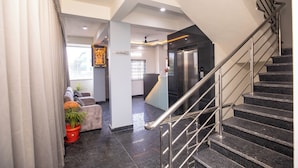 A modern hotel lobby with a staircase, a reception desk, and a seating area with a potted plant. - Hotel Miracle Meridian  (Bengaluru)