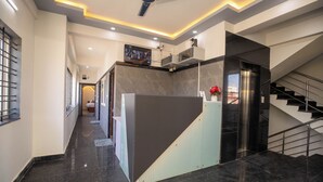 A modern hotel lobby with a reception desk, a staircase, and a ceiling fan. - Hotel Miracle Meridian  (Bengaluru)