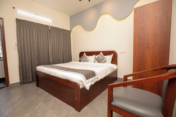 A bedroom with a wooden bed, grey curtains, a wooden chair, and a modern wall design. - Hotel Miracle Meridian (Bengaluru)