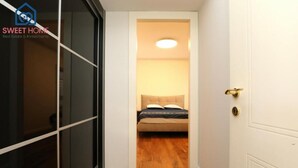 A narrow hallway leading to a bedroom with a bed and a ceiling light. - Sea view family relax apartment (Netanya)