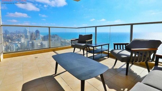 A balcony with a city view, a table, and two chairs. - Sea view family relax apartment (Netanya)