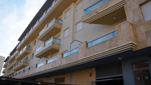 Un immeuble à plusieurs étages, doté de balcons, d’un toit plat et d’une façade en briques.