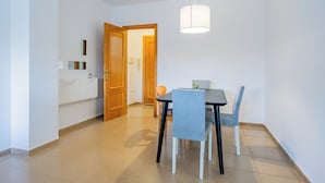 Un espace repas comprenant une table et des chaises, un luminaire suspendu et une porte en bois donnant sur une autre pièce.