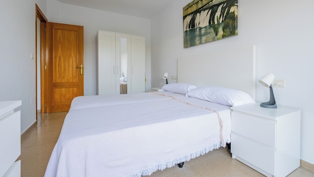 Une chambre à coucher avec un lit, une table de chevet, une commode et un tableau au mur.