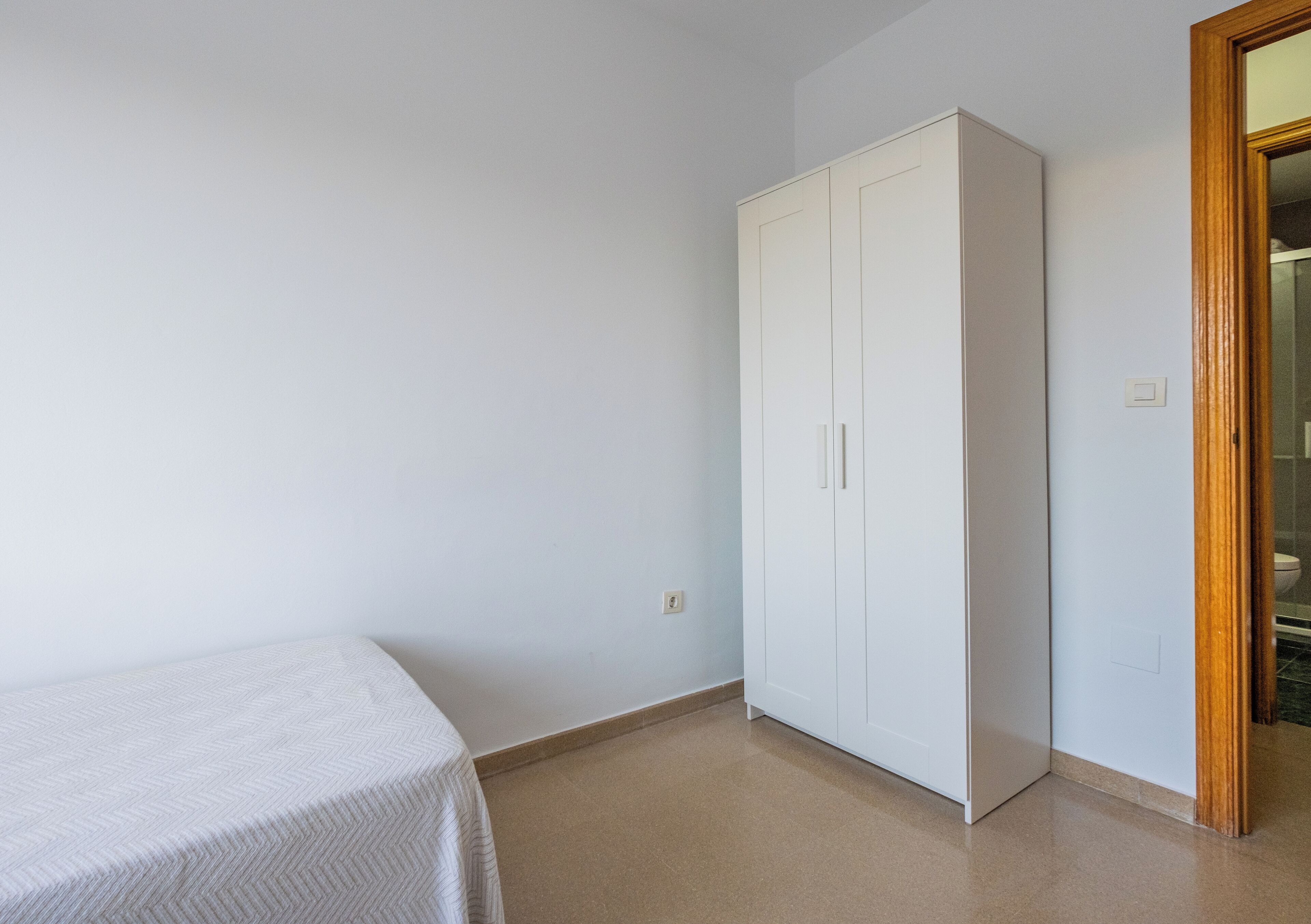 Una habitación con cama, armario y puerta que da a un baño.