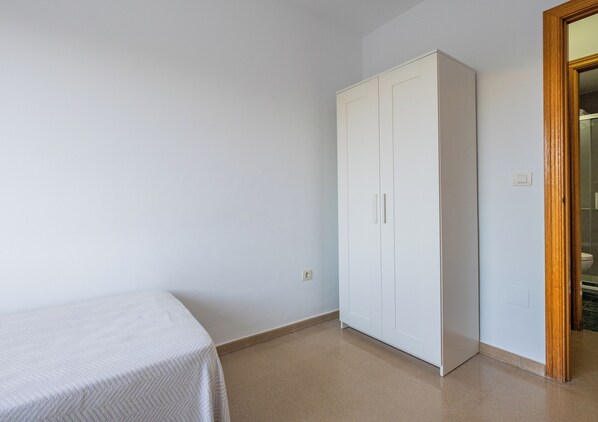 A room with a bed, a wardrobe, and a door leading to a bathroom. - Apartamentos Proamar  (Torre del Mar)