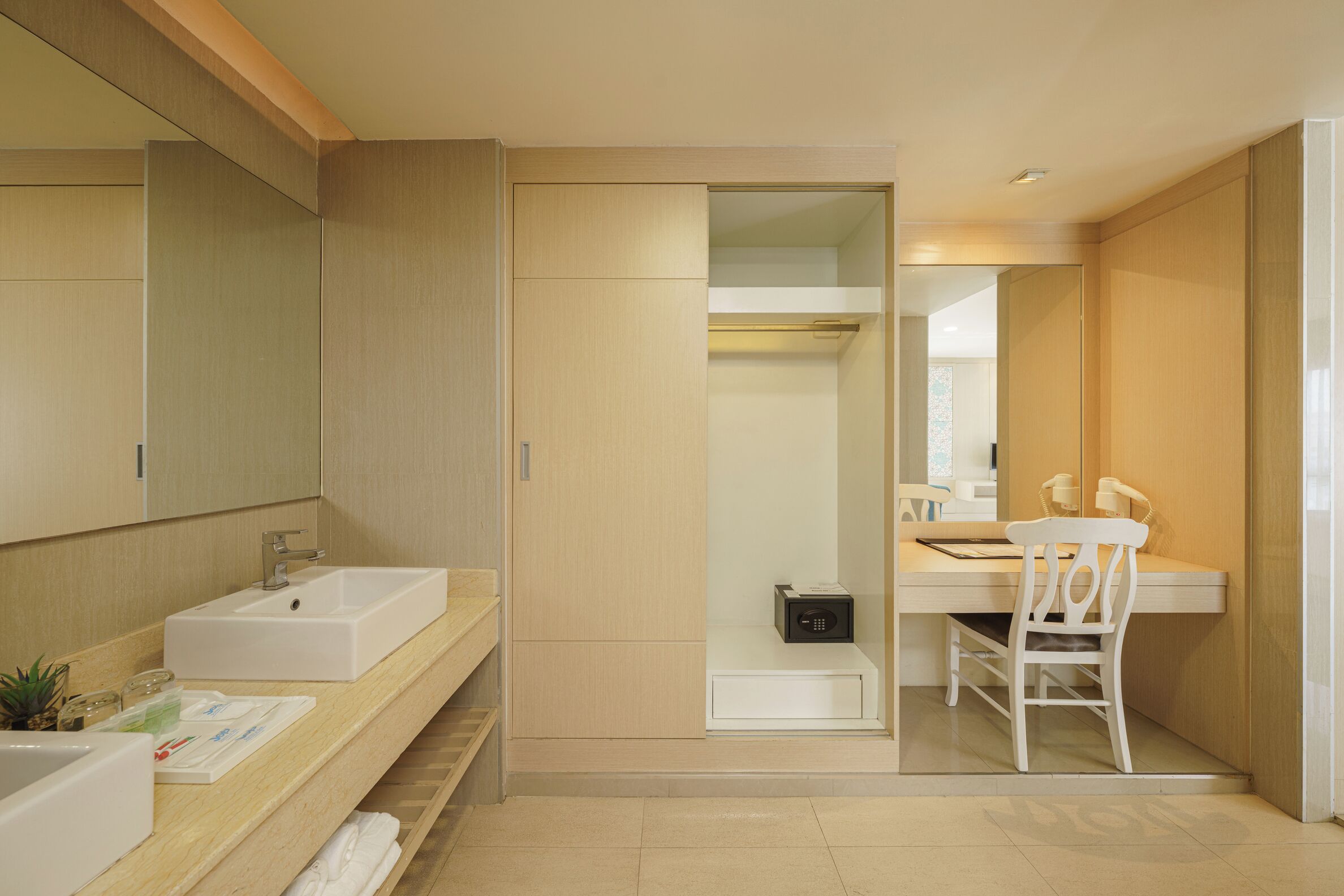A modern bathroom with a large mirror, a sink, and a chair.