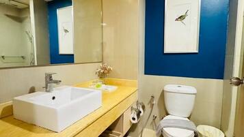 Uma casa de banho moderna com lavatório branco, espelho, sanita e chuveiro.