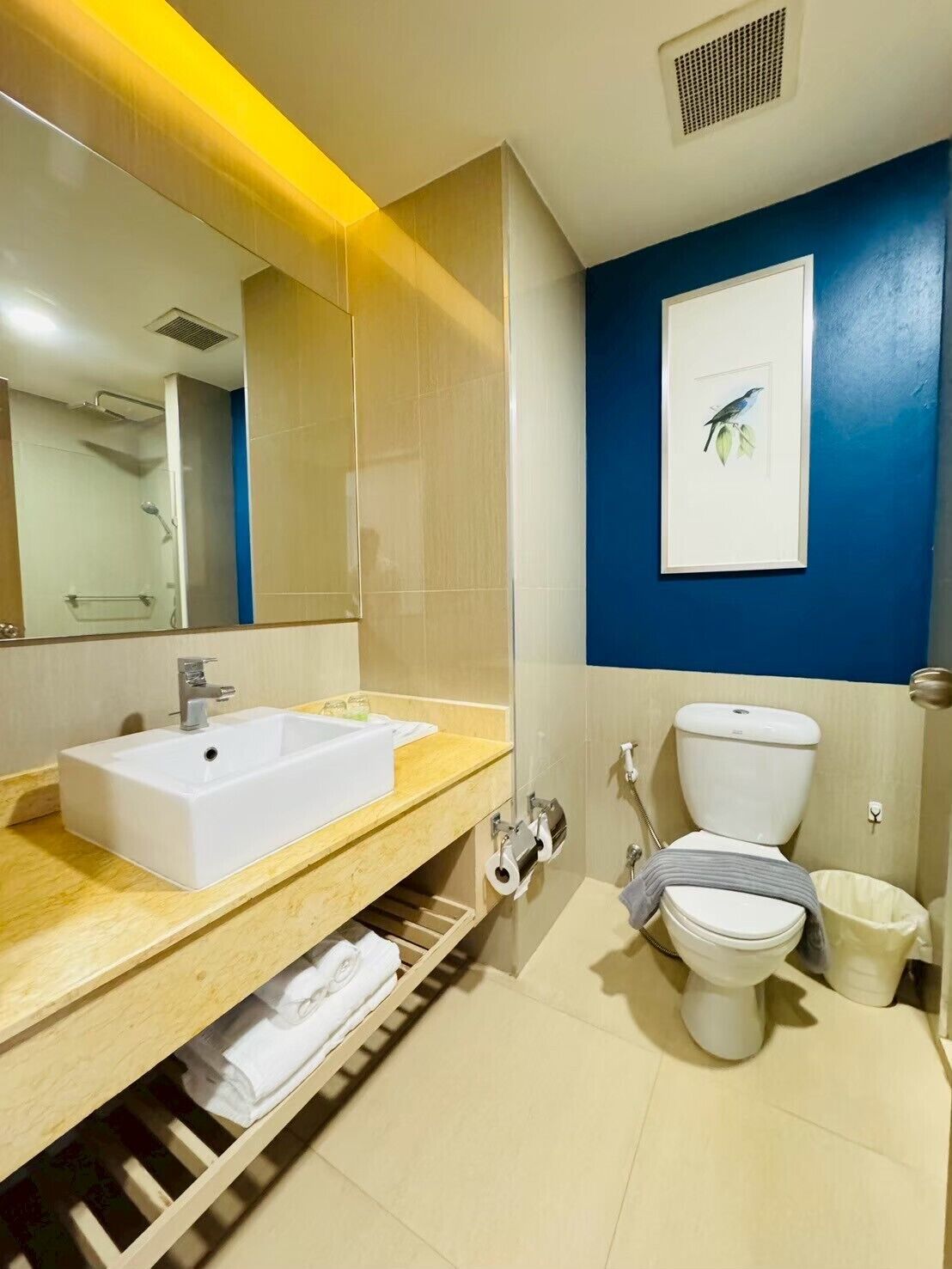 Un baño moderno con un espejo grande, un lavabo blanco, un inodoro y una ducha.