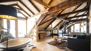Un interno rustico con travi in legno, un tavolo da pranzo, un divano e un'ampia finestra.