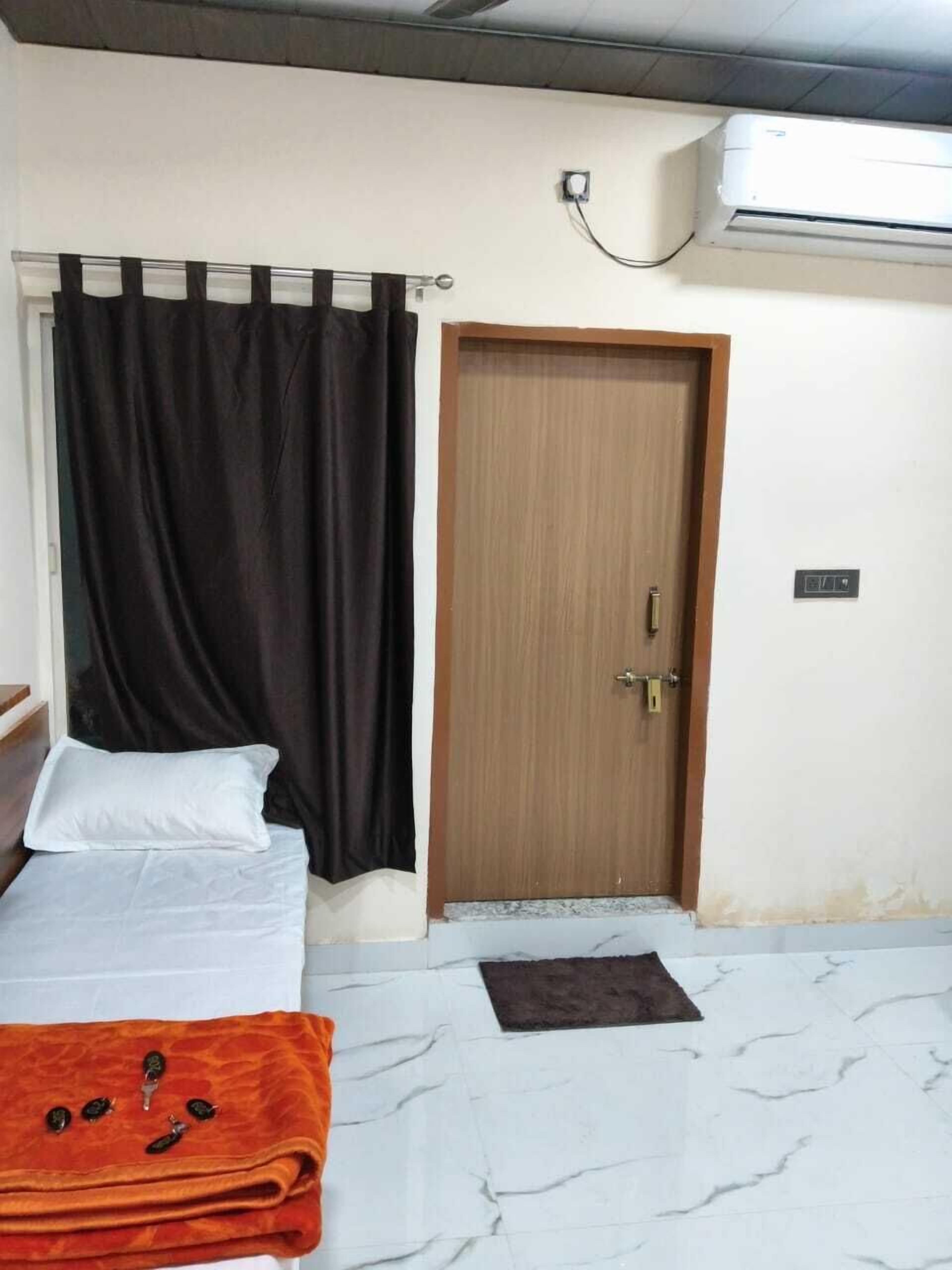 A bedroom with a bed, a wooden door, and an air conditioning unit on the wall.