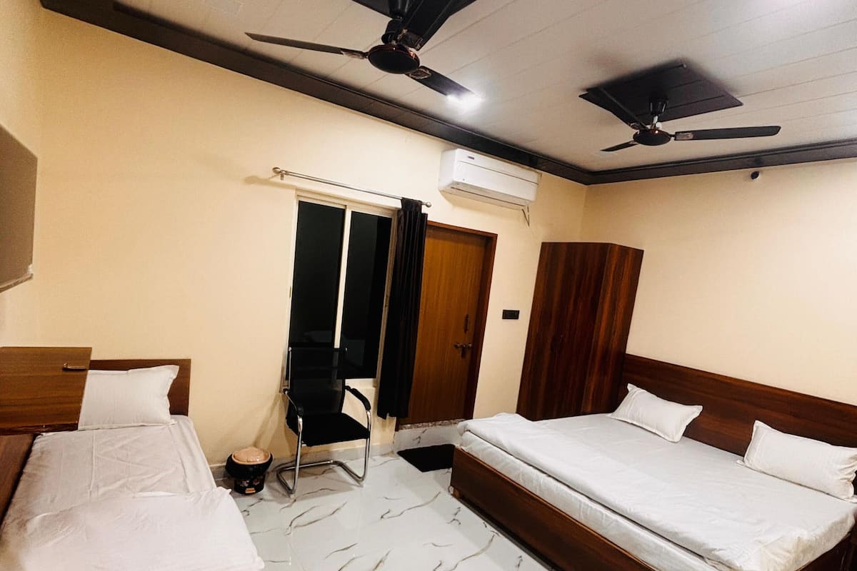 A bedroom with two beds, a ceiling fan, an air conditioning unit, and a door with a curtain.