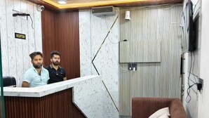 A reception area with a marble counter, a brown sofa, and a striped wall. - Krishna Residency By Vrindavan Stays (Mathura)