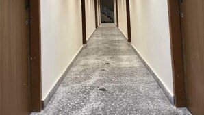 A hallway with wooden doors on either side, a striped ceiling, and a marble floor. - Krishna Residency By Vrindavan Stays (Mathura)