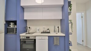 Une cuisine moderne avec des meubles bleus, un plan de travail blanc et un lave-vaisselle.