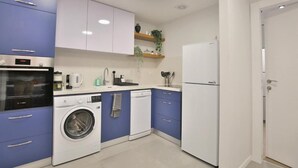 Une cuisine compacte équipée d’un lave-linge, d’un réfrigérateur et d’un four à micro-ondes.