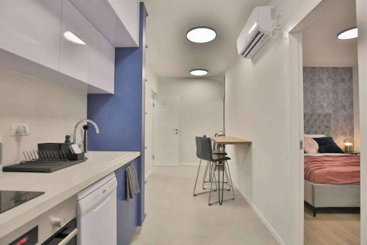 Una habitación de hotel pequeña con kitchenette, comedor y cama.