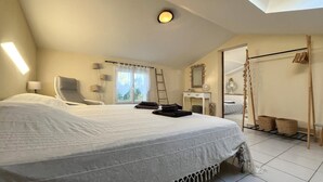 Une chambre à coucher avec un grand lit, une table de chevet, un miroir, une armoire et une fenêtre avec des rideaux.