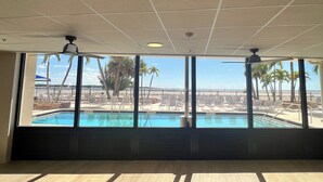 Una habitación con un amplio ventanal con vistas a una piscina y sillas de playa.