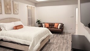A modern bedroom with a large bed, a brown sofa, and a ceiling fan.