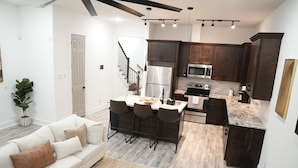 A modern kitchen with dark wood cabinets, a stainless steel refrigerator, and a built-in microwave.
