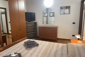 A bedroom with a bed, a dresser, a TV, a mirror, and a lamp. - Free Park and Swimming Pool, Centre of Peschiera (Peschiera del Garda)