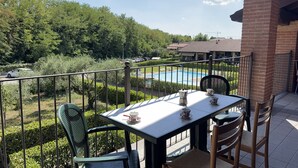 A balcony with a table and chairs, overlooking a swimming pool and greenery. - Free Park and Swimming Pool, Centre of Peschiera (Peschiera del Garda)