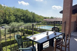 A balcony with a table and chairs, overlooking a swimming pool and greenery. - Free Park and Swimming Pool, Centre of Peschiera (Peschiera del Garda)