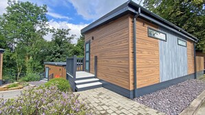Una moderna cabina di legno con un piccolo portico, una porta e una finestra.