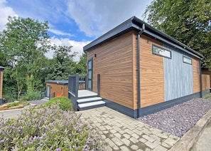 Une cabane en bois moderne, dotée d’un petit porche, d’une porte et d’une fenêtre.
