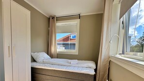 A small, neatly arranged bedroom with a bed, a wardrobe, and a window providing a view of a building outside. - Forenom Serviced Apartments Stavanger (Stavanger)