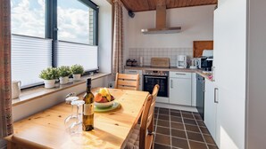 A modern kitchen with a wooden table, a bottle of wine, and a bowl of fruit. - Teutoburger Wald 1 by Interhome (Schwalenberg)