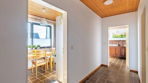 A hallway with a wooden ceiling, tiled floor, and a dining area with a table and chairs. - Teutoburger Wald 1 by Interhome (Schwalenberg)
