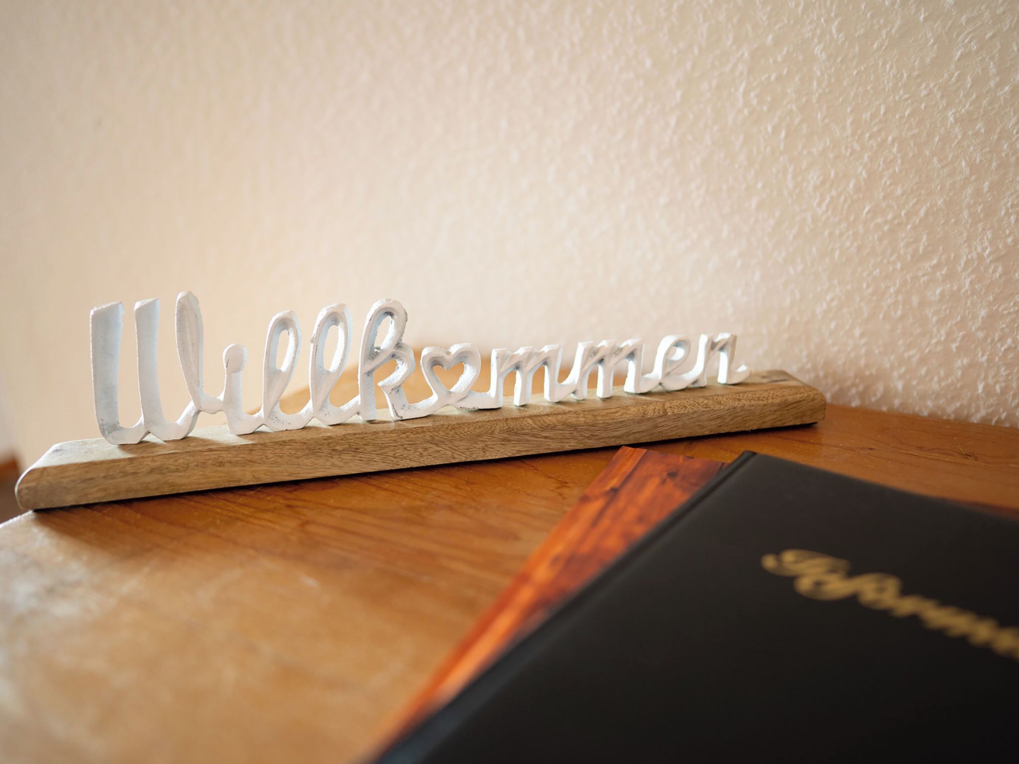 Una placa de madera con la palabra 'Welcome' en una fuente decorativa, sobre una superficie de madera.