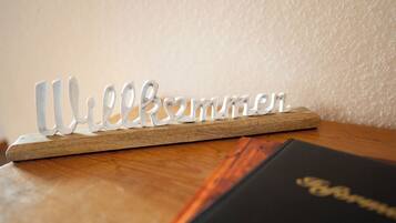 Una placa de madera con la palabra 'Welcome' en una fuente decorativa, sobre una superficie de madera.