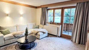 Un salón acogedor con un sofá modular, una mesa de centro y un pequeño árbol de Navidad.