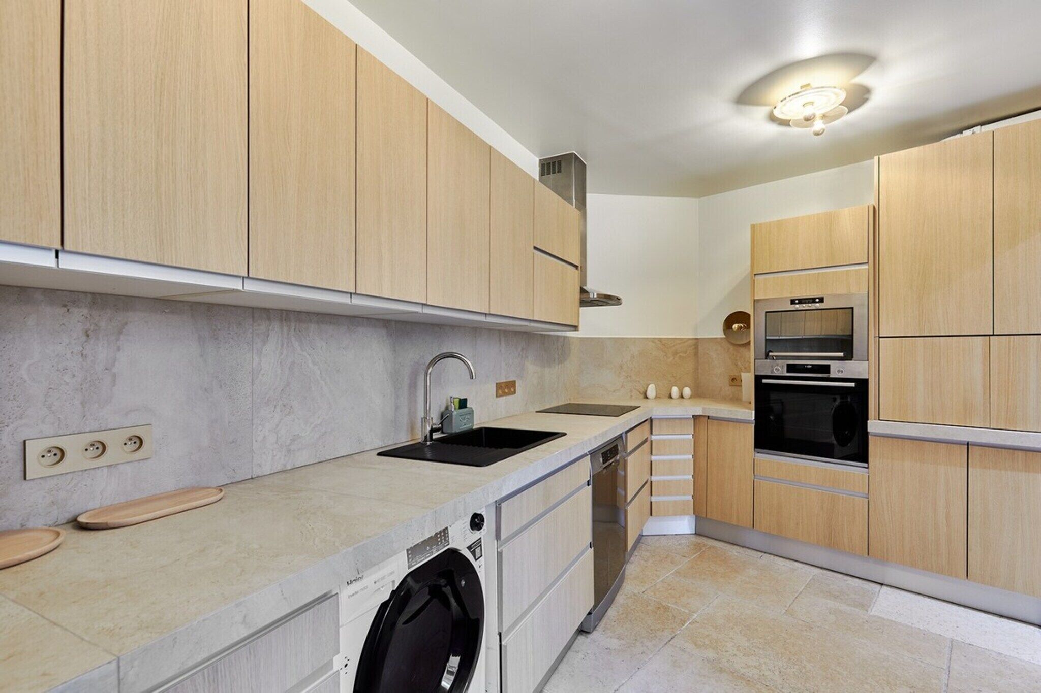 A modern kitchen with wooden cabinets, a built-in dishwasher, a double sink, and a microwave.