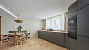A modern kitchen with a herringbone floor pattern, a dining area with a round table and chairs, and built-in appliances.