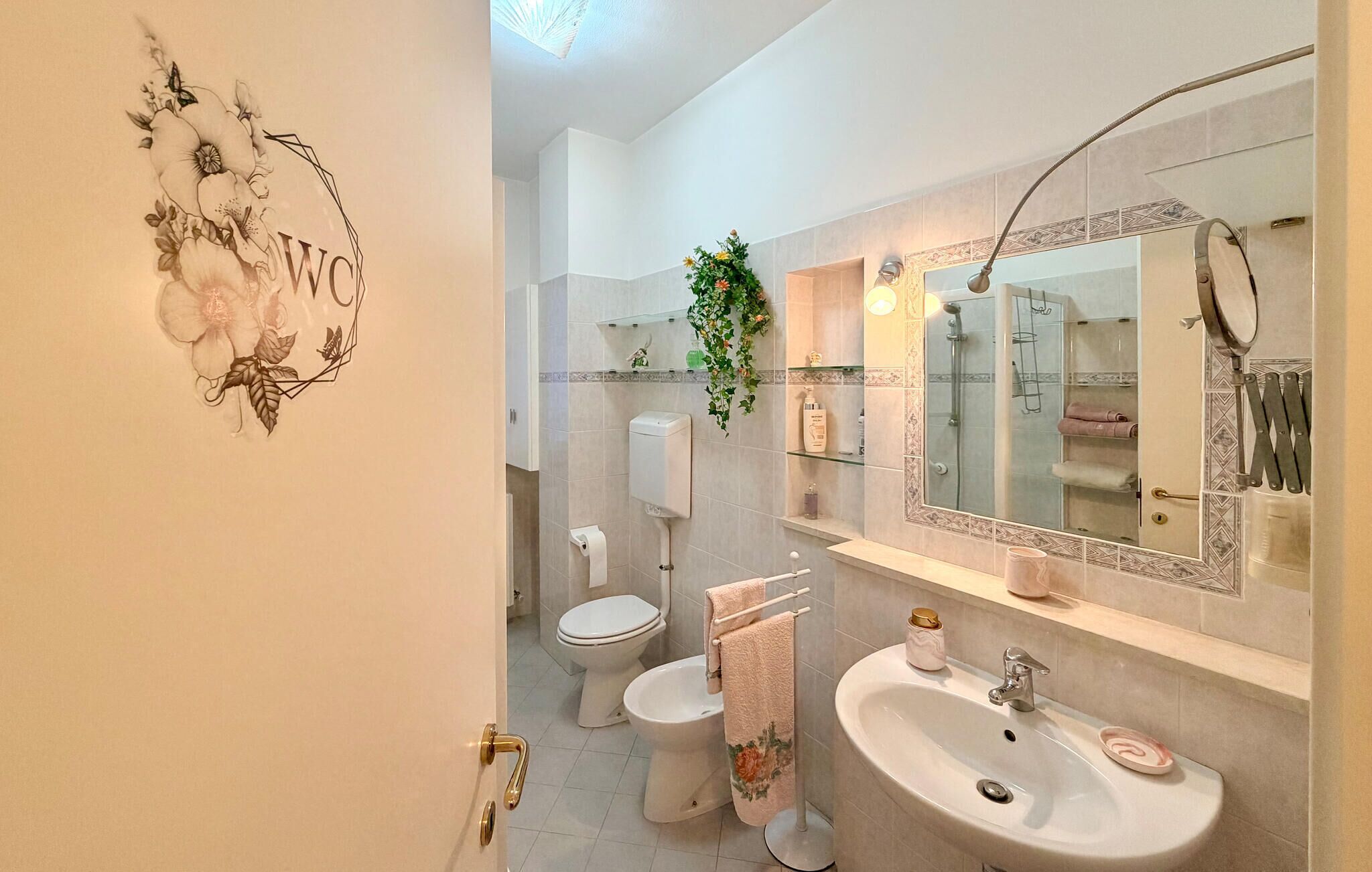 Une salle de bain comprenant des toilettes, un bidet, un lavabo et un miroir, ainsi qu’une douche.