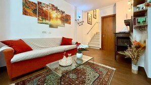 A living room with a sofa, a coffee table, a rug, and a staircase leading to another room. - 3 bedroom awesome apartment in Peglio (Peglio)