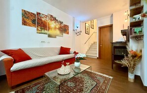 Ein Wohnzimmer mit einer Couch, einem Couchtisch, einem Teppich und einer Treppe, die in einen anderen Raum führt.