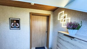 A hallway with a wooden door, a framed picture on the wall, a potted plant, and a modern light fixture. - Alexanders Domizil by Interhome (Schonach)
