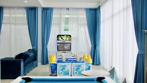 Ein Zimmer mit Poolbillard, einer Couch und einem Spielbereich für Kinder mit Spielzeug und einem Fernseher.
