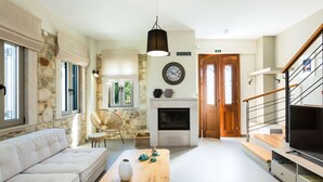 Een ruime woonkamer met een open haard, een bank, een eettafel en een televisie.