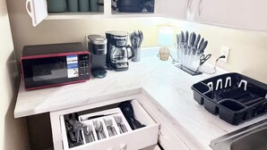 Eine Küche mit Mikrowelle, Kaffeemaschine und Geschirr auf der Arbeitsfläche.