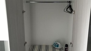 Un placard avec plusieurs étagères, une tringle pour suspendre les vêtements et une serviette pliée.