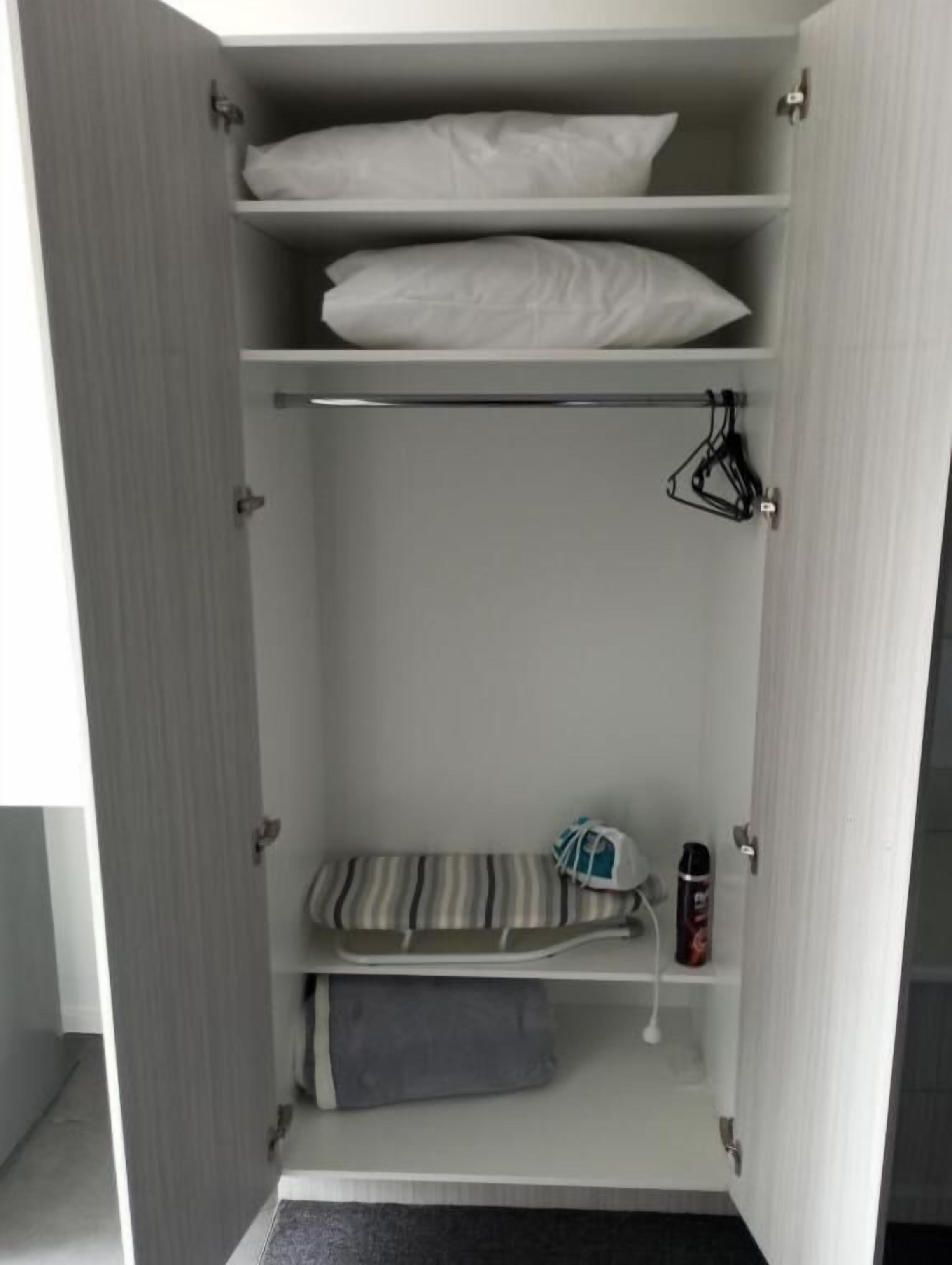 Un armario con varios estantes, una barra para colgar ropa y una toalla doblada.